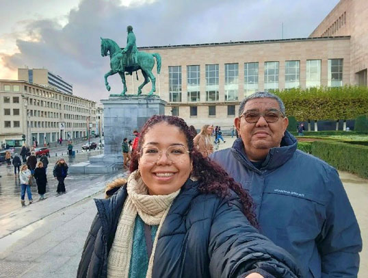 Karen-Stash-and-father-for-web | NJ Sharing Network Two people posing for a selfie in a city square in front of a green equestrian statue on a pedestal.