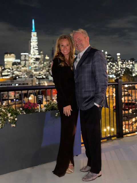 Jessica-and-Dr-Michael-Zampieri-pic-2 | NJ Sharing Network Couple posing on a rooftop balcony at night with city lights behind them.