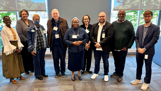 Faith-Leaders-Summit---October-8-2026 | NJ Sharing Network Diverse group of ten adults posing together in a bright conference room, all wearing name badges.